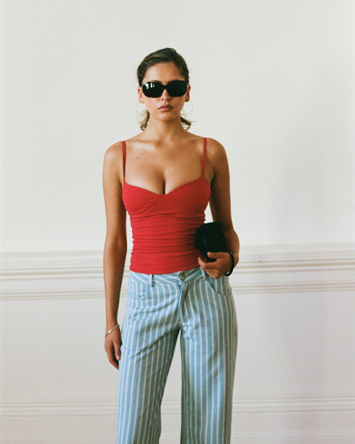 Women's singlet top in deep red colour featuring figure-hugging fit, contoured waist, and bust gathering.